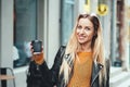 Take away coffee. Beautiful young urban woman wearing in stylish clothes holding coffee cup and smiling while walking along the st Royalty Free Stock Photo