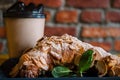 Take away coffee and fresh croissant with mint on wooden background. Cardboard cup with face cap concept Royalty Free Stock Photo