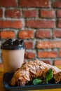 Take away coffee and fresh croissant with mint on wooden background. Cardboard cup with face cap concept Royalty Free Stock Photo