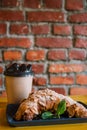 Take away coffee and fresh croissant with mint on wooden background. Cardboard cup with face cap concept Royalty Free Stock Photo