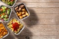 Take away healthy food in foil boxes on wooden table Royalty Free Stock Photo