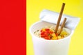 Take away noodles with vegetables on red and yellow background Royalty Free Stock Photo