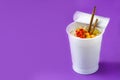 Take away noodles with vegetables on violet background Royalty Free Stock Photo