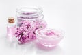 Take bath with lilac cosmetic set and blossom on white table background Royalty Free Stock Photo