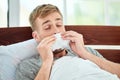 Take care of yourself. Portrait of a sick young man with runny nose suffering from cold or flu and sneezing while lying Royalty Free Stock Photo