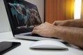 Take a close-up of male hands and laptops with a white world, graph, and cogs on screen. A notebook computer, white mouse, and