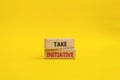 Take initiative symbol. Wooden blocks with words Take initiative. Beautiful yellow background. Business and Take initiative