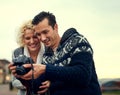 Take a look at this photograph. a young couple looking at photos while on vacation.