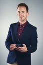 Take my digits and lets do business. Studio portrait of a confident young businessman using a mobile phone against a