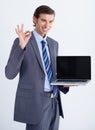 Take my word for it. A young businessman endorsing a laptop with an a okay hand sign.