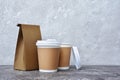 Take-out blank paper coffee cups with white covers, craft cup holders and brown packet Royalty Free Stock Photo