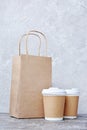 Take-out blank paper coffee cups with white covers, craft cup holders and brown packet Royalty Free Stock Photo