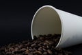 Take-out coffee cup with spilled coffee beans, black background. Coffee beans Royalty Free Stock Photo