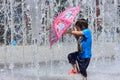 take red umbrel girl playing by water fountain