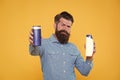 Take this shampoo. Bearded man hold shampoo bottles yellow background. Hipster with beard and mustache choose hair Royalty Free Stock Photo