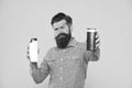 Take this shampoo. Bearded man hold shampoo bottles yellow background. Hipster with beard and mustache choose hair Royalty Free Stock Photo