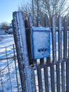 Snow-covered wooden fence with mailbox