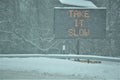 Take It Slow message visible on electronic road sign during snowstorm Royalty Free Stock Photo
