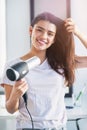 Take the time to care for your hair. Portrait of a beautiful young woman blowdrying her hair in the bathroom at home.