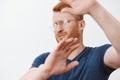 Take this ugly thing away from me. Displeased intense redhead mature guy in glasses and blue t-shirt, turning away and Royalty Free Stock Photo