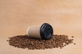 Takeaway brown paper coffee cup with black cap lie on roasted beans at brown background. Mock up Royalty Free Stock Photo