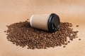 Takeaway brown paper coffee cup with black cap lie on roasted beans at brown background. Mock up Royalty Free Stock Photo