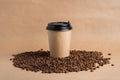 Takeaway brown paper coffee cup with black cap stands on roasted beans at brown background. Mock up Royalty Free Stock Photo