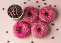 Takeaway coffee cup with coffee beans and pink glaze donuts with colorful sprinkles, pink background. Top view Royalty Free Stock Photo