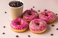 Takeaway coffee cup with coffee beans and pink glaze donuts with colorful sprinkles, pink background Royalty Free Stock Photo