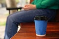 Takeaway coffee cup and woman on bench outdoors
