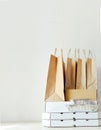 Takeaway paper bags and carton boxes on table in white bright room. Takeout meal