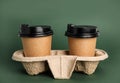 Takeaway paper coffee cups with plastic lids in holder on dark green background Royalty Free Stock Photo