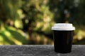 Takeaway paper cup with plastic lid on stone parapet outdoors, space for text Royalty Free Stock Photo