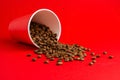 Takeaway red paper coffee cup on red background with pouring roasted beans out of it. Mock up Royalty Free Stock Photo