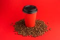 Takeaway red paper coffee cup with black cap stand on roasted beans at red background. Mock up Royalty Free Stock Photo