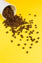 Takeaway white paper coffee cup on yellow background with pouring roasted beans out of it Royalty Free Stock Photo