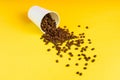 Takeaway white paper coffee cup on yellow background with pouring roasted beans out of it Royalty Free Stock Photo