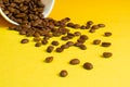 Takeaway white paper coffee cup on yellow background with pouring roasted beans out of it Royalty Free Stock Photo