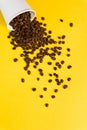Takeaway white paper coffee cup on yellow background with pouring roasted beans out of it Royalty Free Stock Photo