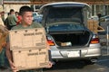 Military personnel load supplies into civilian cars.