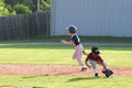 Little League Softball Player dashes for third base while second baseman reaches for ball