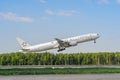 Takeoff Boeing 777 Singapore Airlines against the backdrop of the forest. White jet Boeing 777 9V-SWI. Moscow Domodedovo