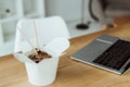 takeout box with chinese noodles and chopsticks on table with laptop Royalty Free Stock Photo