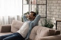 Peaceful young man recline on sofa breath deep enjoy nap