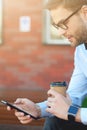 Taking a break at work. Side view of a handsome businessman using smartphone and drinking coffee while relaxing on the Royalty Free Stock Photo