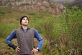 Taking a breath of fresh air. A young man with his hands on his hips looking outwards in the outdoors.