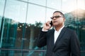 Taking calls on the go. a handsome mature businessman making a phonecall with his office in the background. Royalty Free Stock Photo