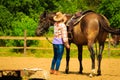 Cowgirl getting horse ready for ride on countryside Royalty Free Stock Photo
