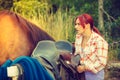 Cowgirl getting horse ready for ride on countryside Royalty Free Stock Photo