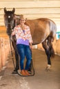 Cowgirl standing next to brown horse friend Royalty Free Stock Photo